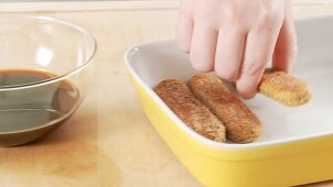 Preparing tiramisu: placing the sponge fingers in a dish