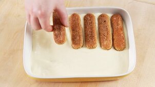 Preparing tiramisu: adding another layer of sponge fingers