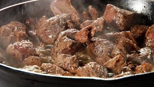 Beef being fried in a pan