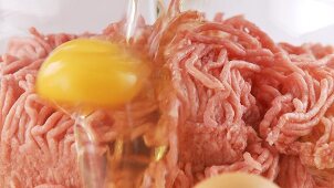 An egg and a bread being added to minced meat