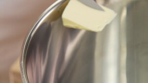 A piece of butter being put into a pan