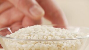 A hand taking a bowl of risotto rice