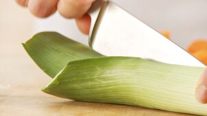 A leek being cut in half lengthways and chopped