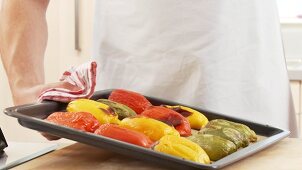 A baking tray of peppers being taken out of the oven