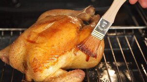 Roast chicken being brushed with spiced butter