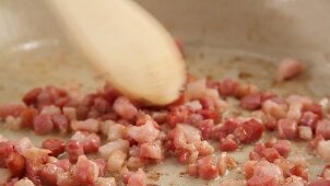 Diced bacon being fried