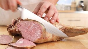 A pink leg of lamb being sliced