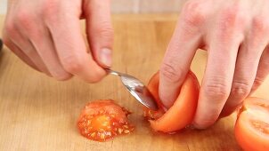 Peeled tomatoes being halved and deseeded