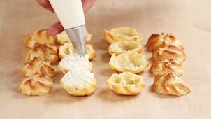 Profiteroles being filled with cream