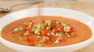 Croutons being sprinkled onto gazpacho