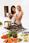 Two young women clinking glasses in kitchen
