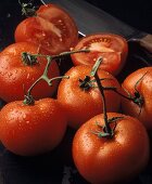 Ganze frische Tomaten mit Wassertropfen & zwei Tomatenhälften