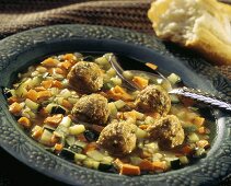 Gemüsesuppe mit Fleischklösschen im Suppenteller mit Löffel