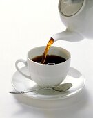 Kaffee aus einer Porzellankanne in eine Tasse gießen