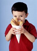 Small boy holding paper bag of strips of pizza 