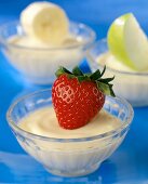 Small Bowls of Vanilla Yogurt with a Strawberry an Apple Slice and a Banana Slice