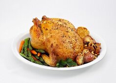 Roasted Chicken on a Platter with Asparagus, Carrots and Potatoes on White
