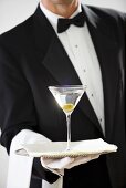 Butler hält Silbertablett mit Martiniglas