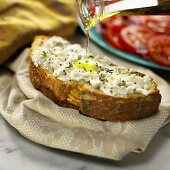 Olive Oil Pouring onto a Slice of Crusty Bread Topped with Goat Cheese
