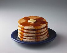 Ein Stapel Pancakes mit Ahornsirup & Butter auf Teller