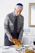 Man Breaking Piece From Challah Bread at Hanukkah Diner Table