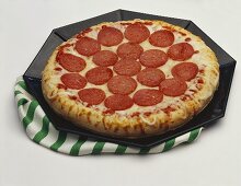 Pizza mit Peperoniwurst auf eckigem Teller