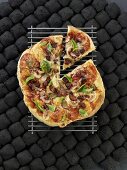 Gegrillte Pizza mit Wurst, Zwiebeln und Basilikum