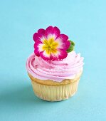 Cupcake mit rosa Buttercreme und pinkfarbener Primel