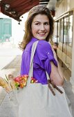 Frau hält Einkaufstasche mit Blumen und Baguette (Paris, Frankreich)