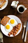 Frühstück mit Spiegelei, Bacon, Toast und Kaffee