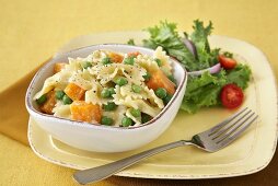 Farfalle Pasta with Peas and Squash in a Bowl; Fork; Side Salad