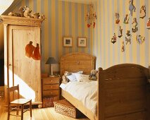 A childrens' room with wooden furniture and stripped wallpaper