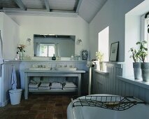 Traditionelles Badezimmer in einem Landhaus mit Terrakottafliesen, einem Holzwaschtisch mit zwei Waschbecken und holzvertäfelten Wänden