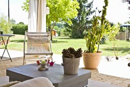 A bucket filled with pince cones on a patio table with view over the garden