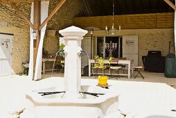 A stone fountain playing on the terrace of a southern house