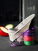 Coils of colourful hose next to a wicker chair and floor lights