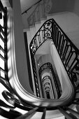 A stairway of a manor house with a black banister