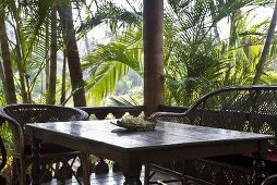 Terrasseneckplatz mit Korbmöbel auf der Veranda in tropischer Umgebung