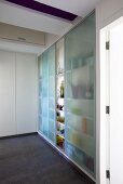 A built-in cupboard full of glasses with sliding doors made of blue grass