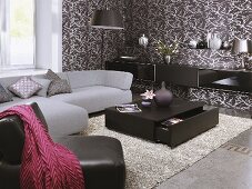 Graues Sofa & schwarzer Ledersessel vor Couchtisch in Wohnraumecke mit braun-weiss gemusterter Tapete
