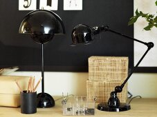 Black table lamps and writing implements on a light colored shelf
