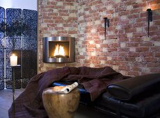 Comfy place to lie down with dark red throw covers in front of a wood burning stove and brick wall