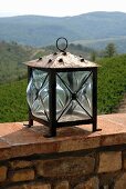 Lantern on a stone wall with a view of a Mediterranean landscape
