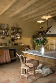 A rustic kitchen with a dining area and a dog lying on a Mediterranean terracotta floor