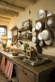A kitchen counter with a rustic wooden work surface and pots and pans hanging on a wooden board