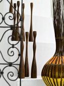 Collection of wooden sculptures next to decorative wrought iron with a floral design and willow basket with colorful fabric strips