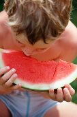 A little boy eating a slice of watermelon