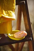 Soap in a yellow bowl and a towel on a wooden ladder