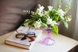 weiße Blumen in rosafarbenem Stielglas