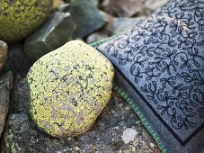 A painted stone and a grey, embroidered felt cushion